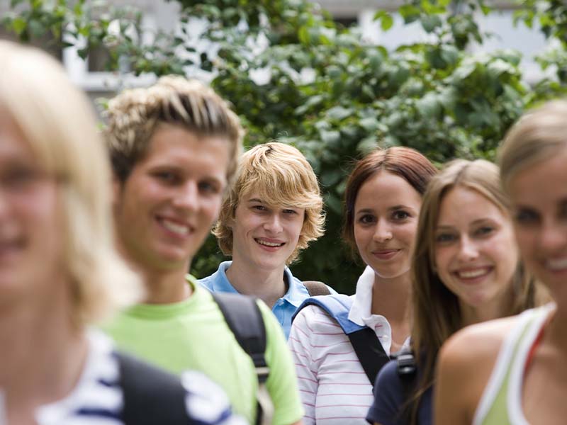 Group of teenagers smiling outside a school building