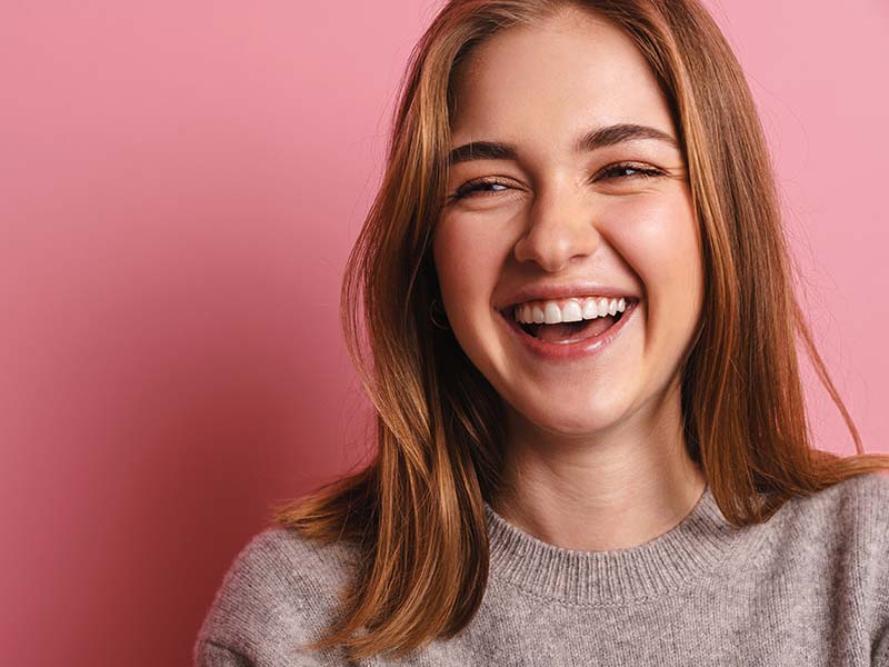 Woman laughing against a pink background