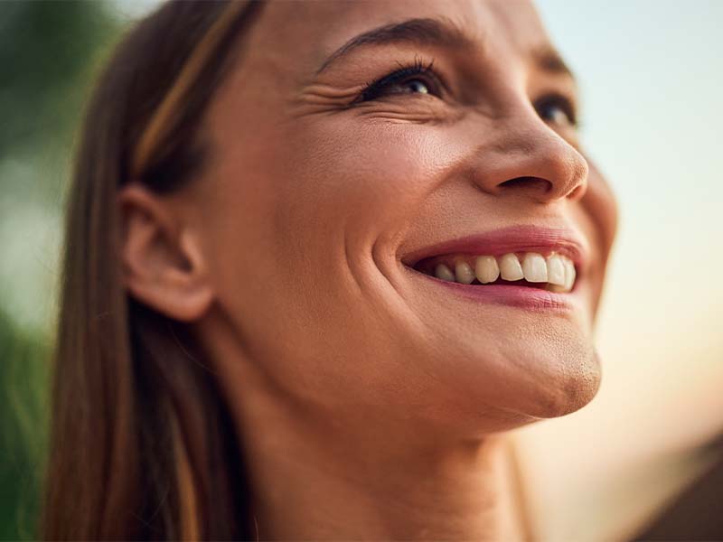 Side profile of a woman smiling outdoors