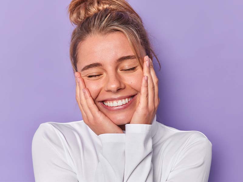 Woman smiling with her hands resting on her face